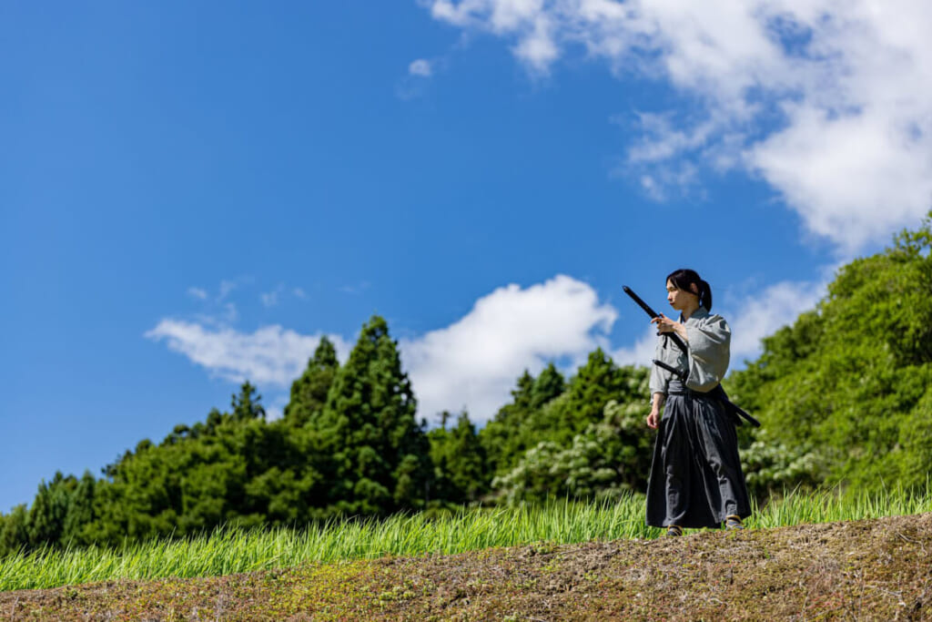 「晴天の草原で遠くを見つめるサムライ」のイメージ画像